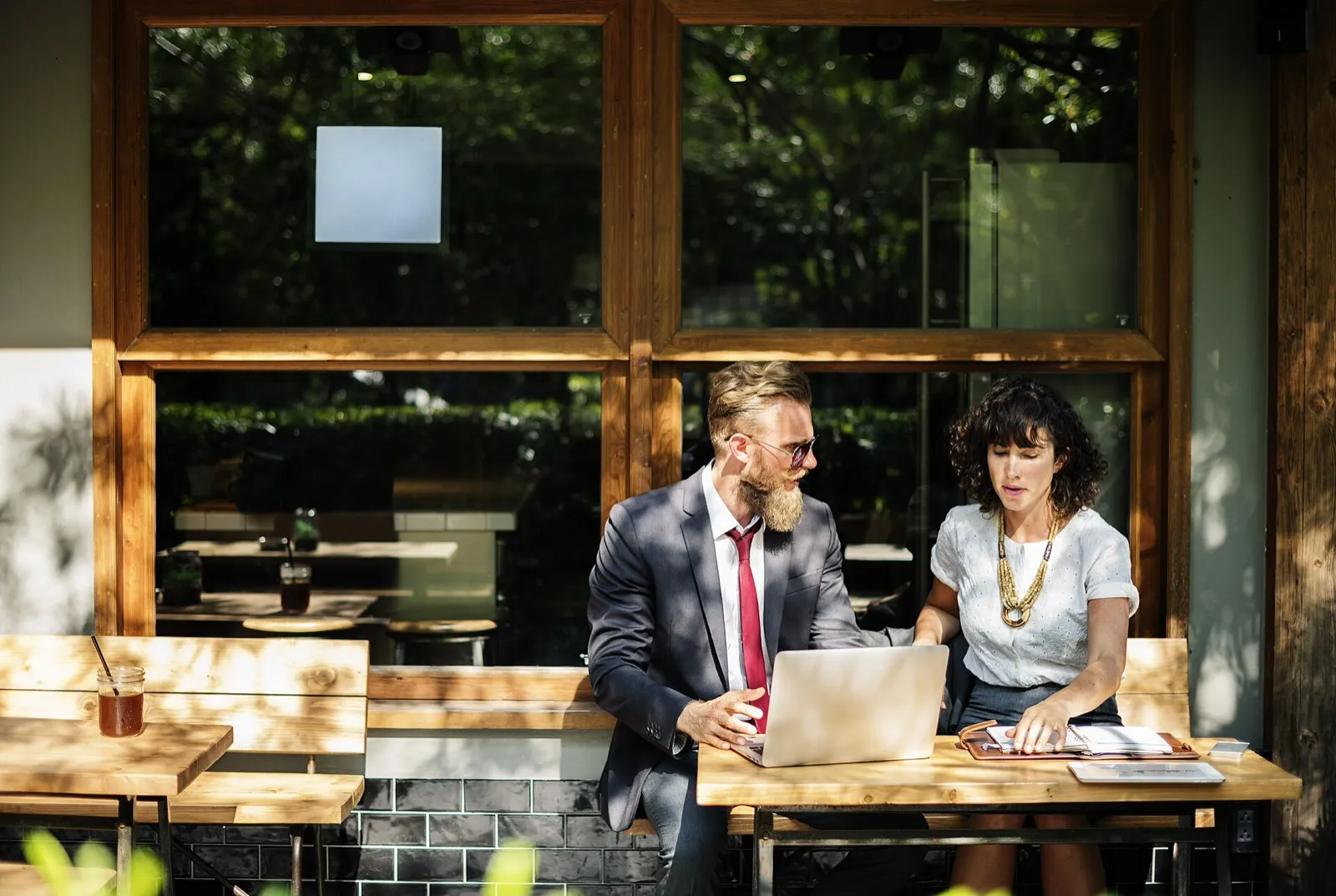An adviser and a client going through figures on a laptop at a window table
