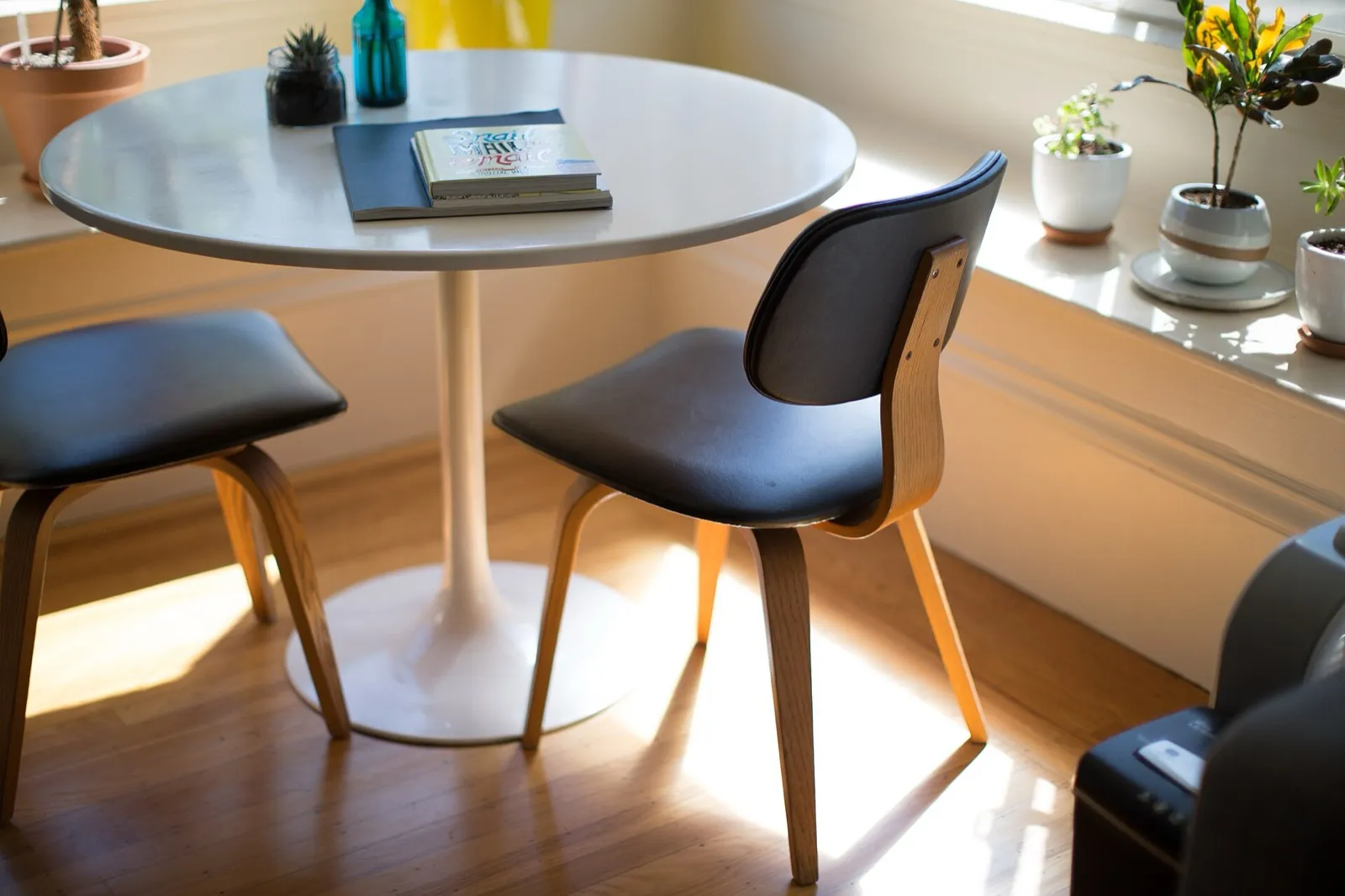 A small round table and two chairs by a sunny window