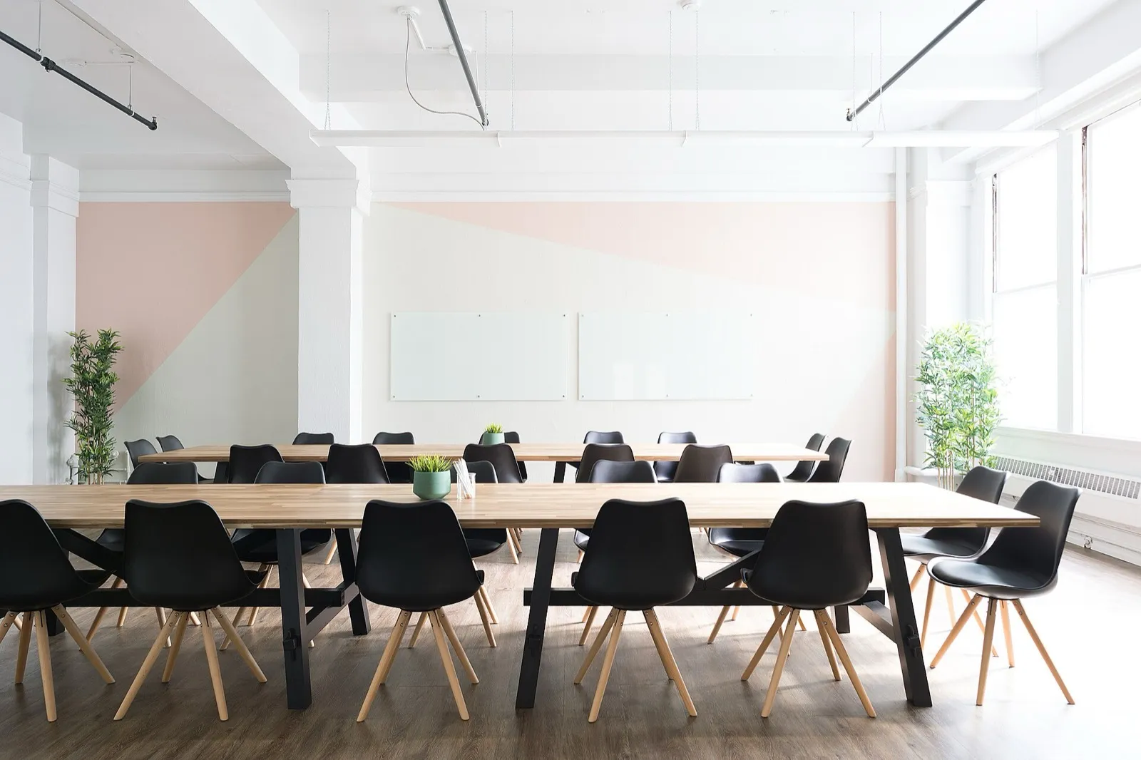 A long meeting table with black chairs in a white, sunlit room